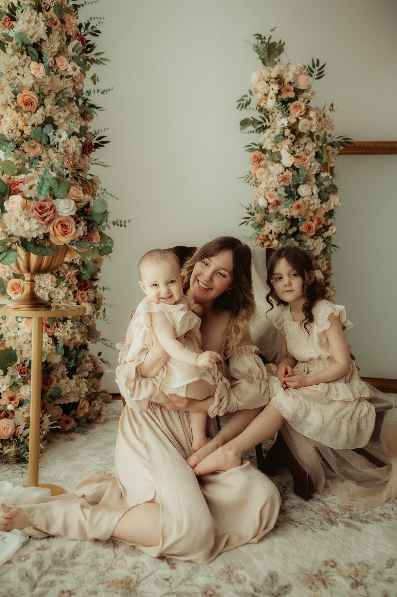 Sarah sitting with her two daughters in a room filled with flowers